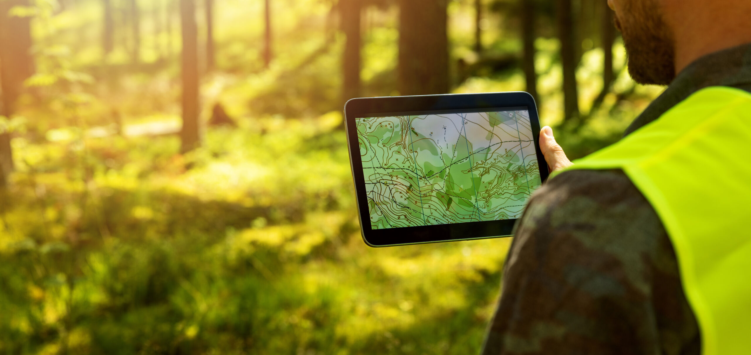 Metsätalousinsinööri työskentelee tabletilla topografisten karttatietojen parissa metsässä.