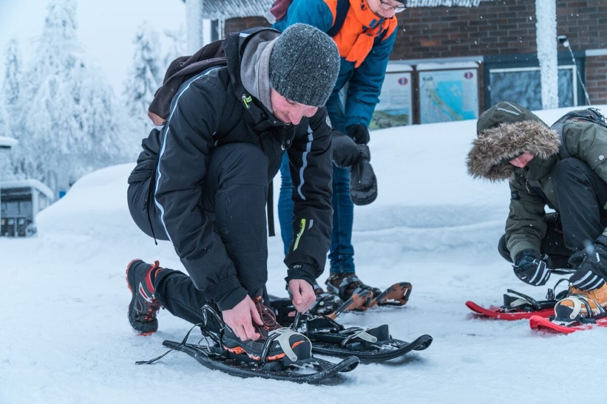 lumikenkää asettava mies