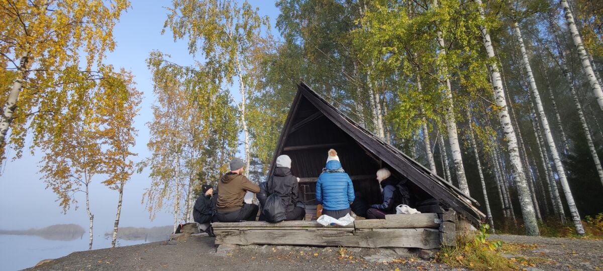 Neljä ihmistä ulkona laavulla.