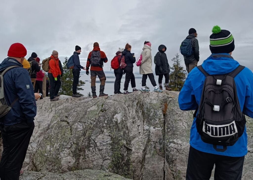 Ryhmä henkilöitä kalliolla ulkoiluvaatteet päällä