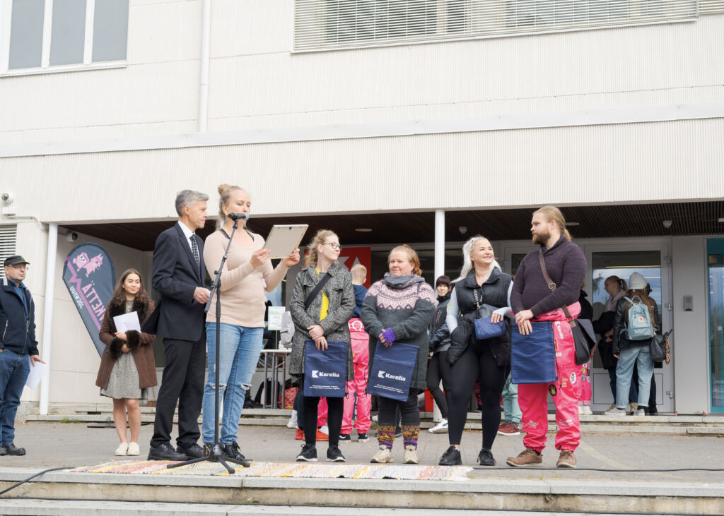 Karelian vararehtori Pekka Auvinen jakaa avajaispalkintoja POKA:n Tiia Kyllösen kanssa. Kuvassa myös neljä palkittua.