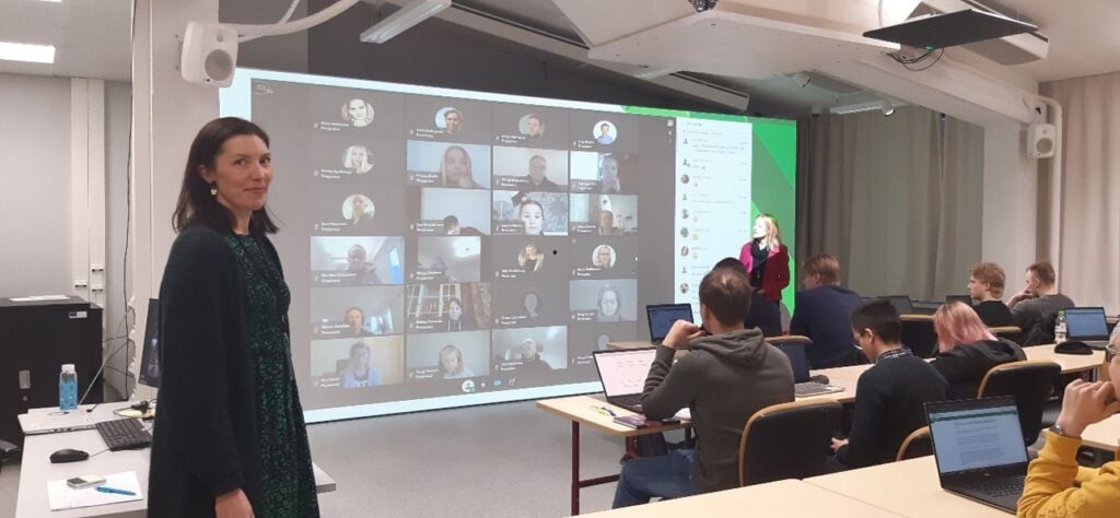 Classroom with students and teachers. Screen with the photos of students who are participating online.